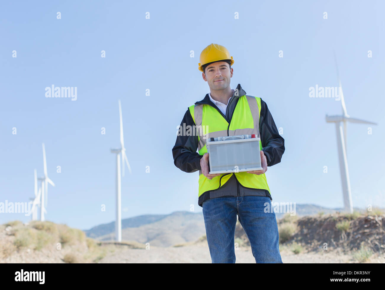Arbeitnehmer, die durch Windkraftanlagen in ländlichen Landschaft stehen Stockfoto