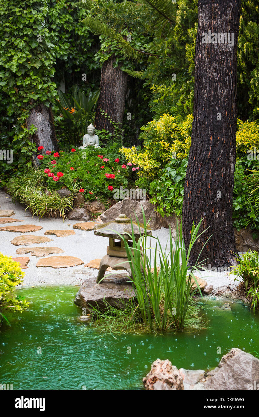 Spanien Europa Garten regnerischen Buddha Wohndesign Tropfen Blumen grüne japanische Gartenlaterne natürliche Natur Pfad Teich Regen sand Stockfoto