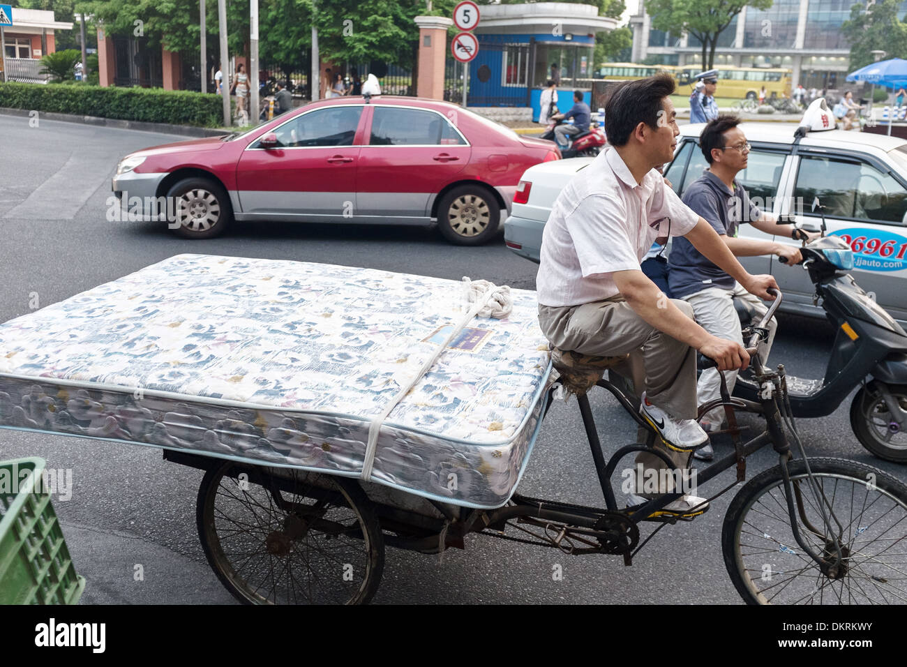Dreirad-Fahrer tragen Matratze in Shanghai, China Stockfoto