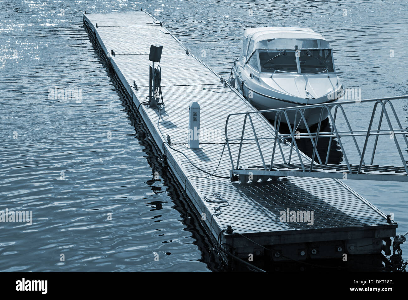 Kleines Motorboot vor Anker in der Nähe von hölzernen Schwimmsteg Stockfoto