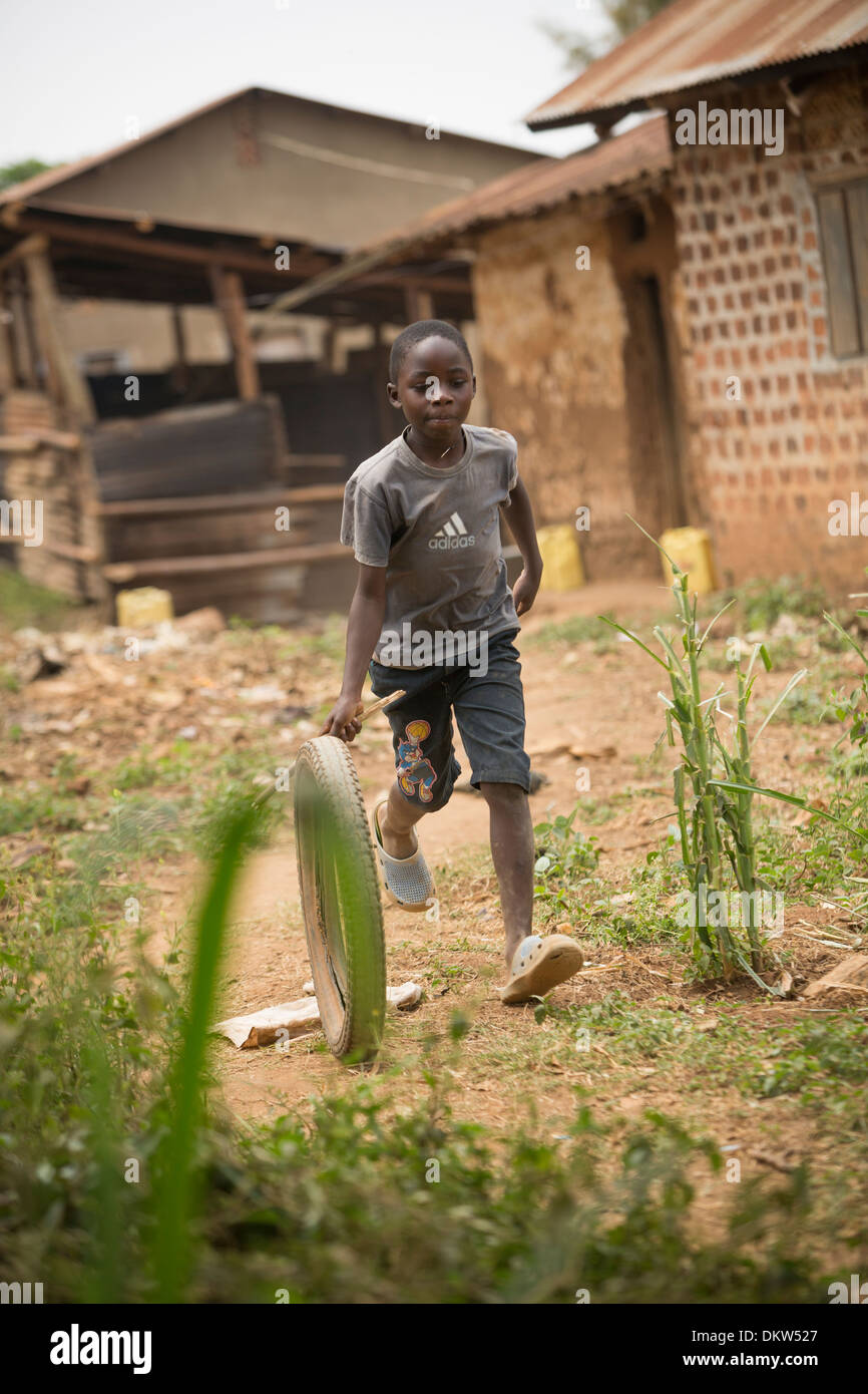 Kinder Rennen mit einem Rad in Uganda Slum - Gombe, Uganda, Ostafrika. Stockfoto