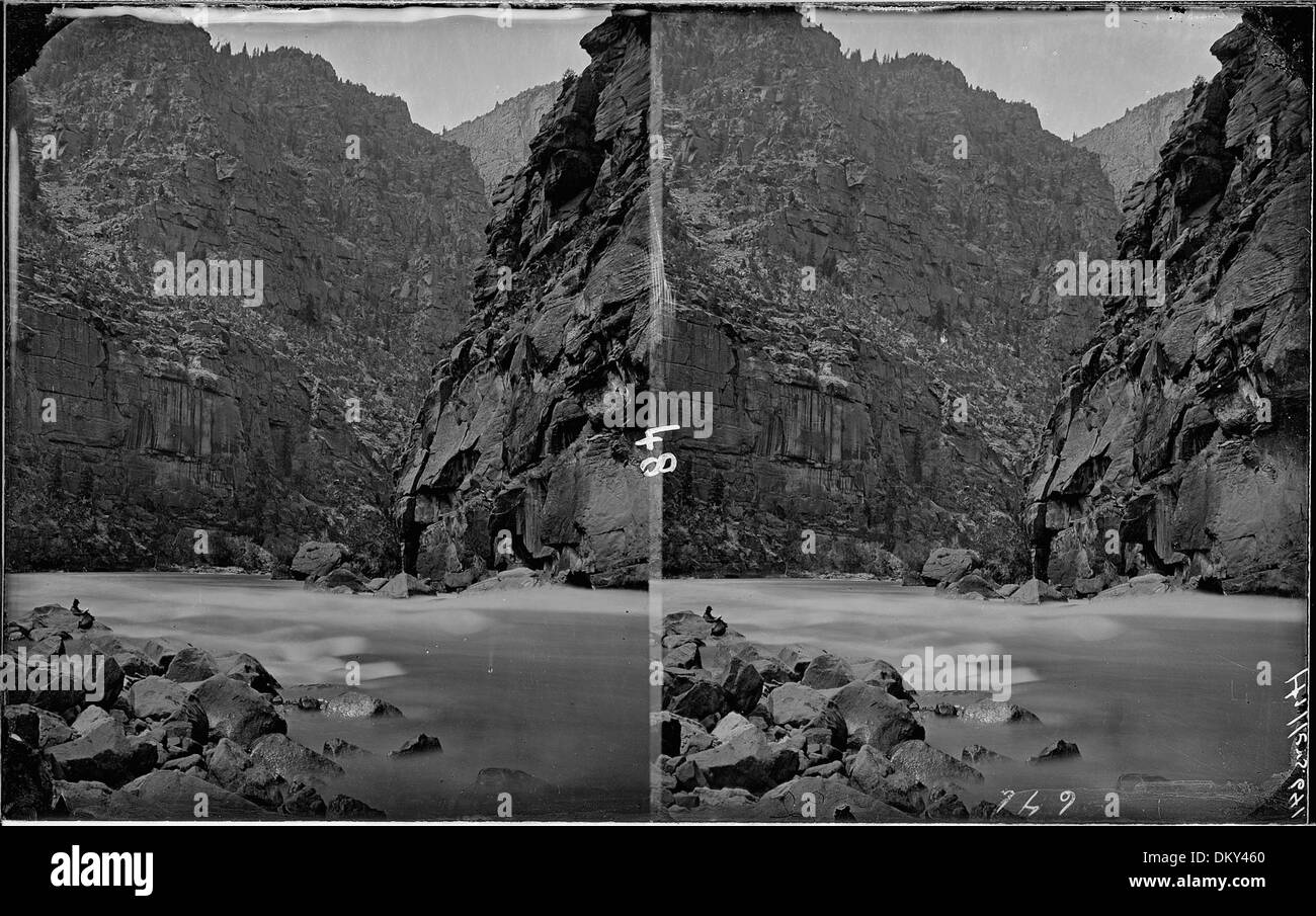 Der Green River im Canyon of Lodore zeigt eine kleine Figur eines Mannes, der am linken Ufer liest, möglicherweise Clem Powell, während einer Erkundungs- oder Flussfahrt. Stockfoto