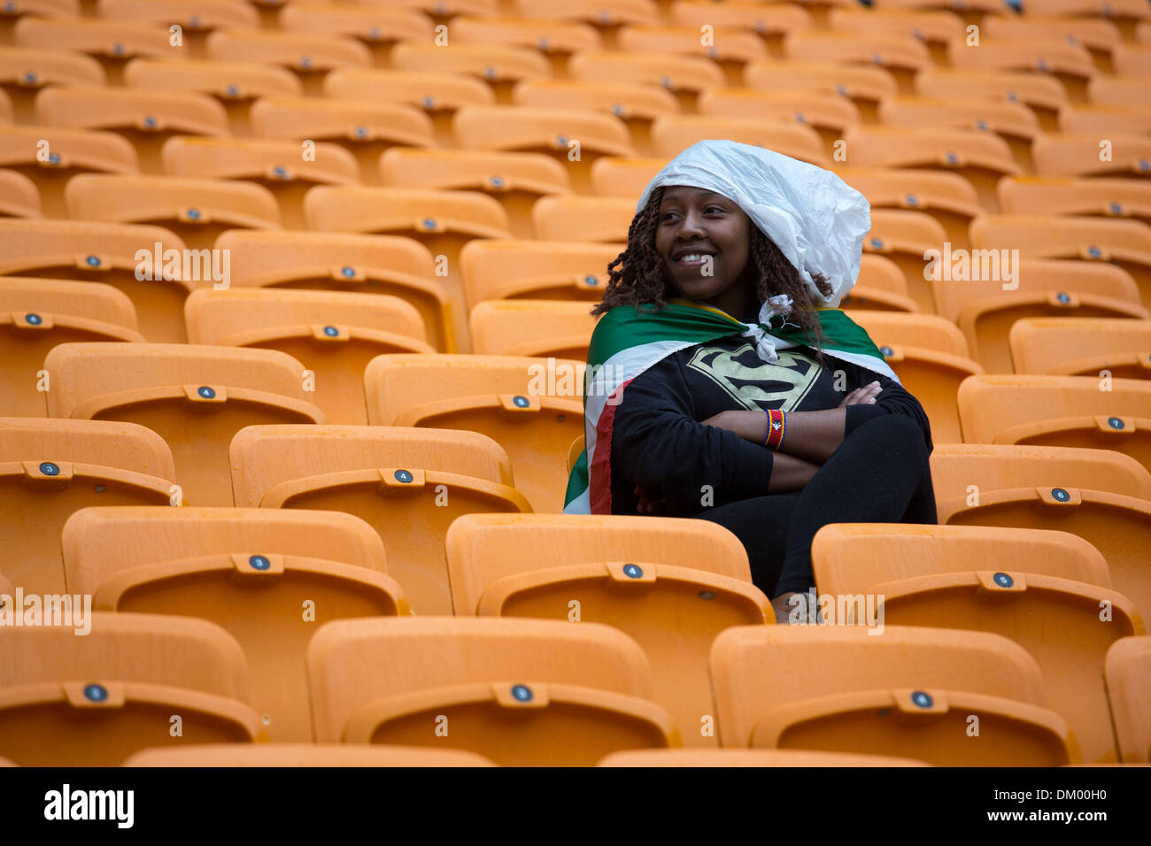 Soweto, Südafrika. 10. Dezember 2013. Eine Frau sitzt im Regen am ehemaligen Präsidenten Nelson Mandela Trauerfeier im FNB-Stadion in Johannesburg, am 10. Dezember 2013 in Soweto, Südafrika statt. Der Vater der Nation starb ruhig am Abend des 5. Dezember 2013 in seinem Haus in Houghton mit Familie. Er wird in Qunu für die offiziellen Staatsbegräbnis am 15. Dezember 2013 begraben werden. Bildnachweis: Gallo Bilder/Alamy Live News Stockfoto