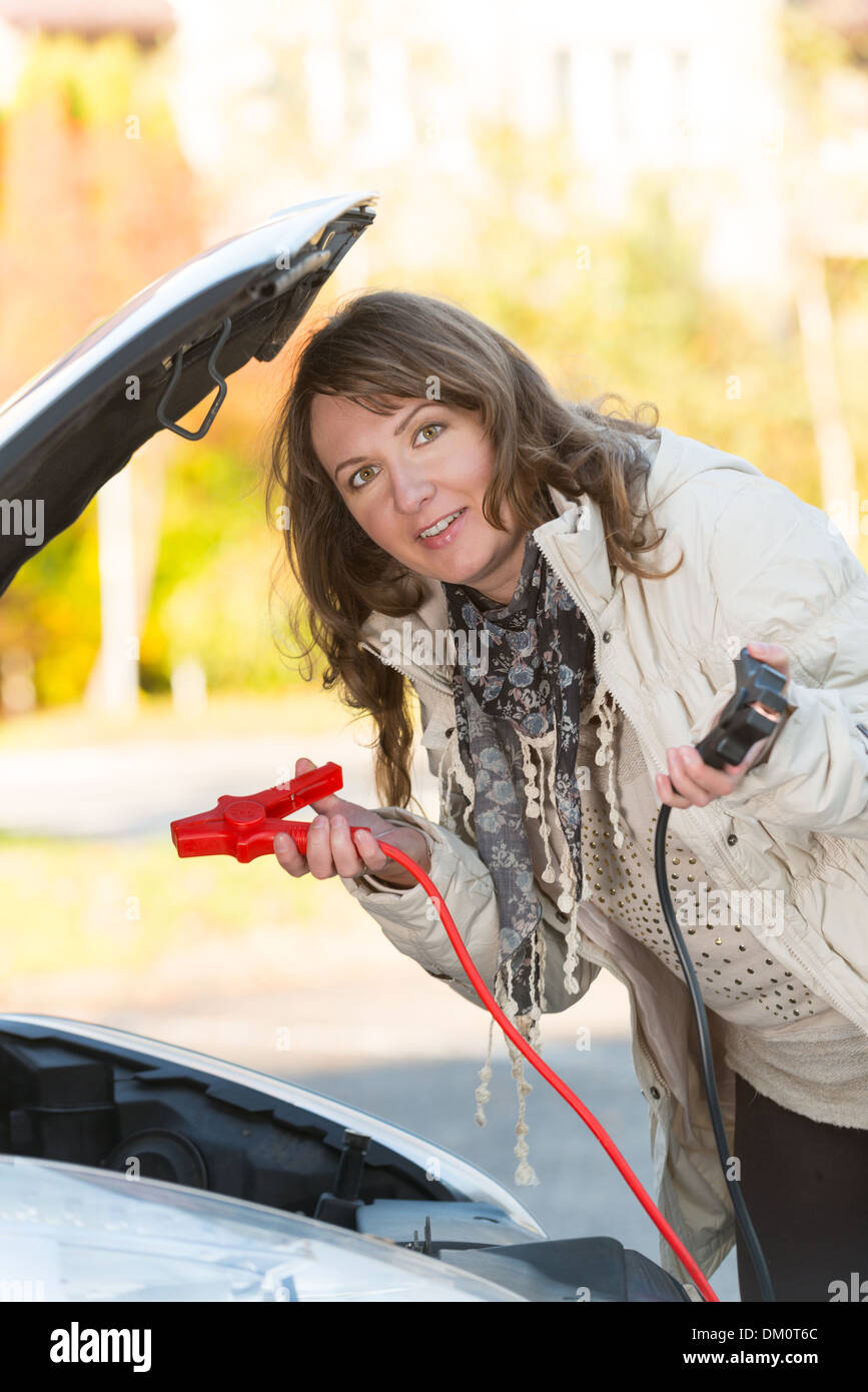 Schöne Frau Booster Anschlusskabel an eine Autobatterie Stockfoto