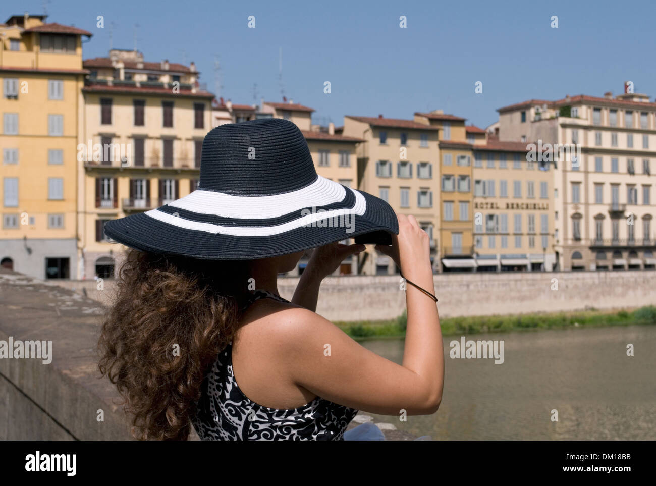 Touristen mit Sonnenhut fotografieren über Arno Fluss, Florenz, Italien Stockfoto