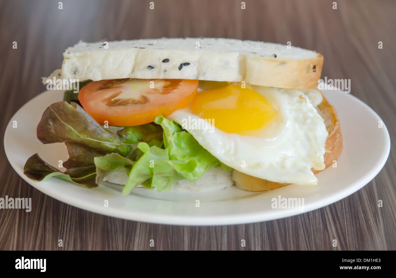 frisches Sandwich mit Tomaten, Salat und Spiegelei auf Teller Stockfoto