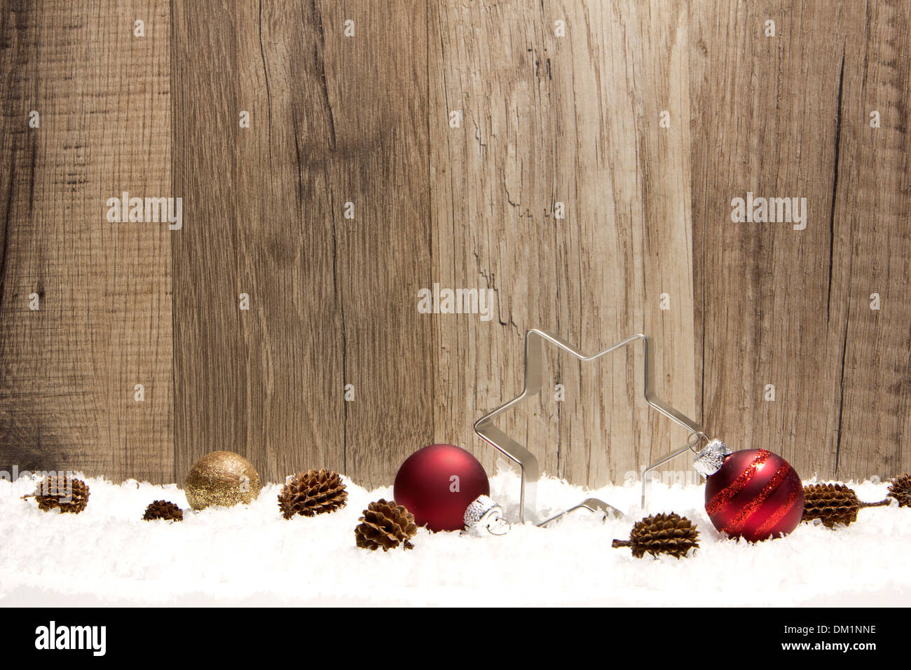 Weihnachts-Dekoration mit hölzernen Hintergrund, Schnee, Weihnachtskugeln rot, Weihnachtsstern und Tannenzapfen Stockfoto