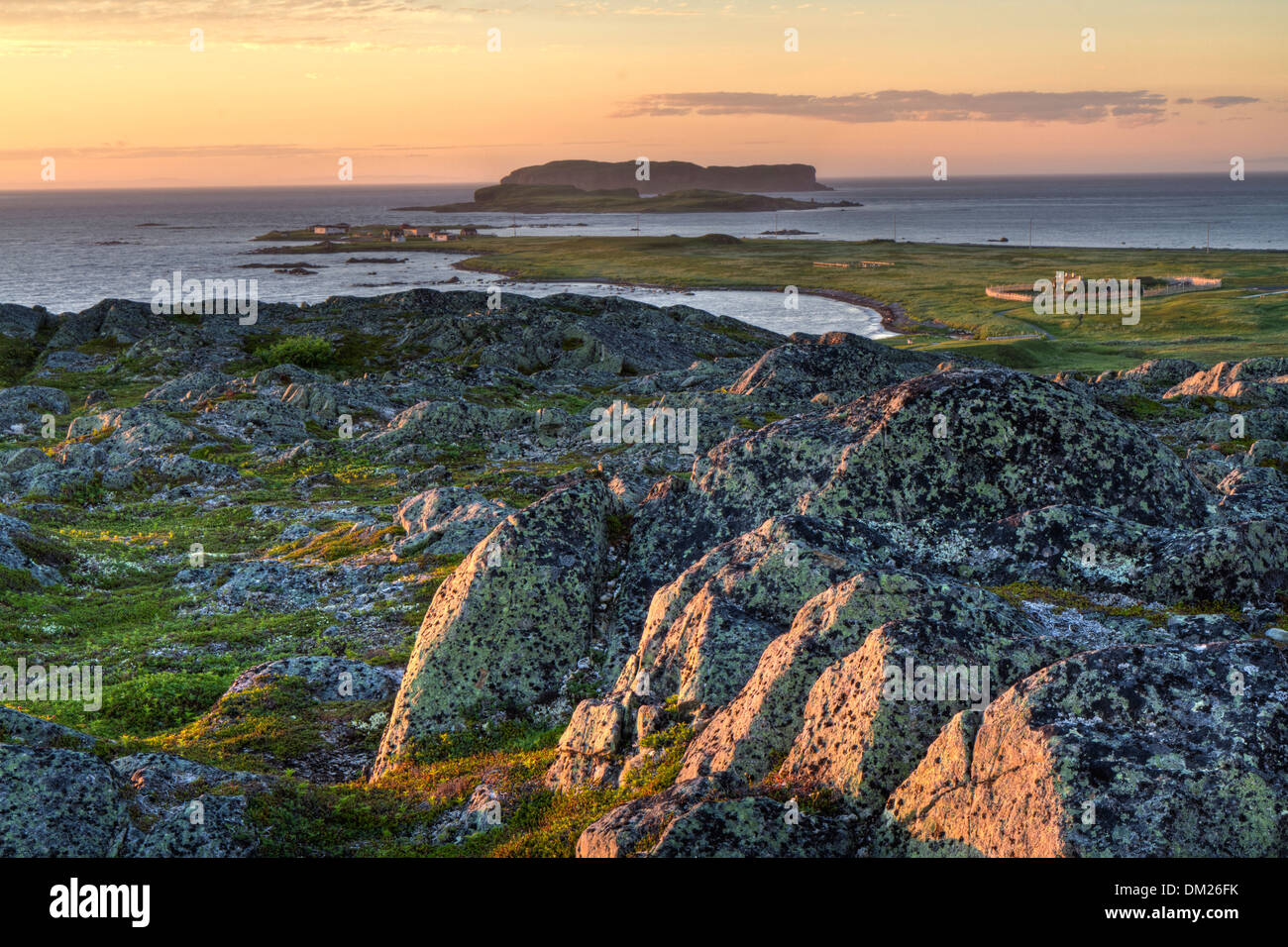 Sonnenuntergang von einem felsigen Hügel mit Blick auf eine Wikinger-Siedlung am L'Anse Aux Meadows National Historic Site in nördlichen Neufundland Stockfoto