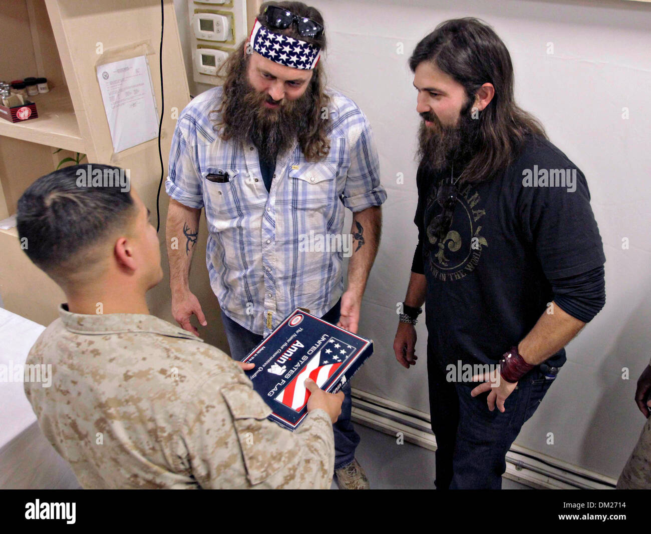 Afghanistan. 10. Dezember 2013. US Marine Staff Sgt Eddy Cuenca präsentiert Duck-Dynastie-Reality-TV-Stars Willie und Jep Robertson mit einer USA-Flagge am Camp Leatherneck 10. Dezember 2013 am Camp Leatherneck, Afghanistan geflogen.  Robertsons Besuch ist Teil der jährlichen USO Urlaub Tour dazu beitragen, die Moral der Service-Mitglieder im Ausland eingesetzt. Bildnachweis: Planetpix/Alamy Live-Nachrichten Stockfoto