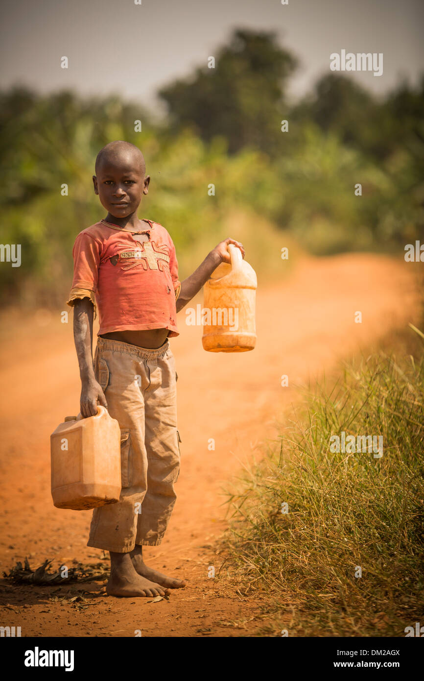 Ein Kind trägt Gießkannen Hause in Gombe, Uganda, Ostafrika. Stockfoto