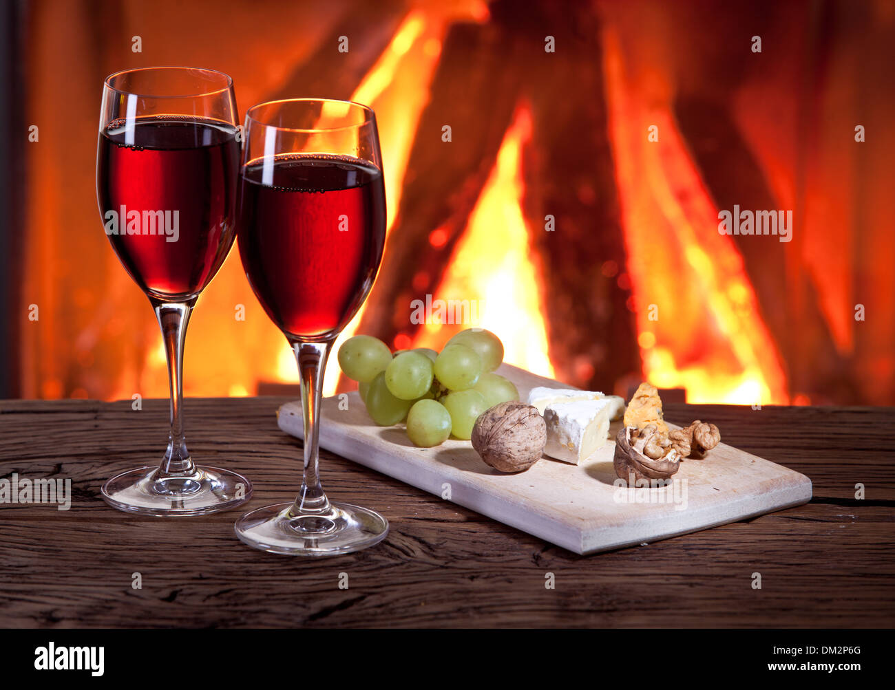 Romantisches Stilleben am Kamin. Gläser Wein, Käse und Nüssen. Stockfoto