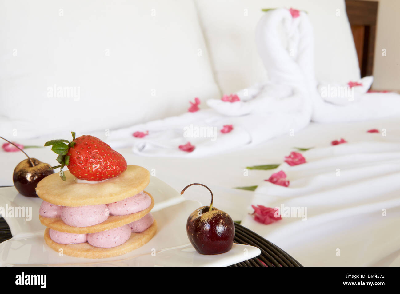 Dessert auf Teller neben dekorierte Hotel Bett Stockfoto