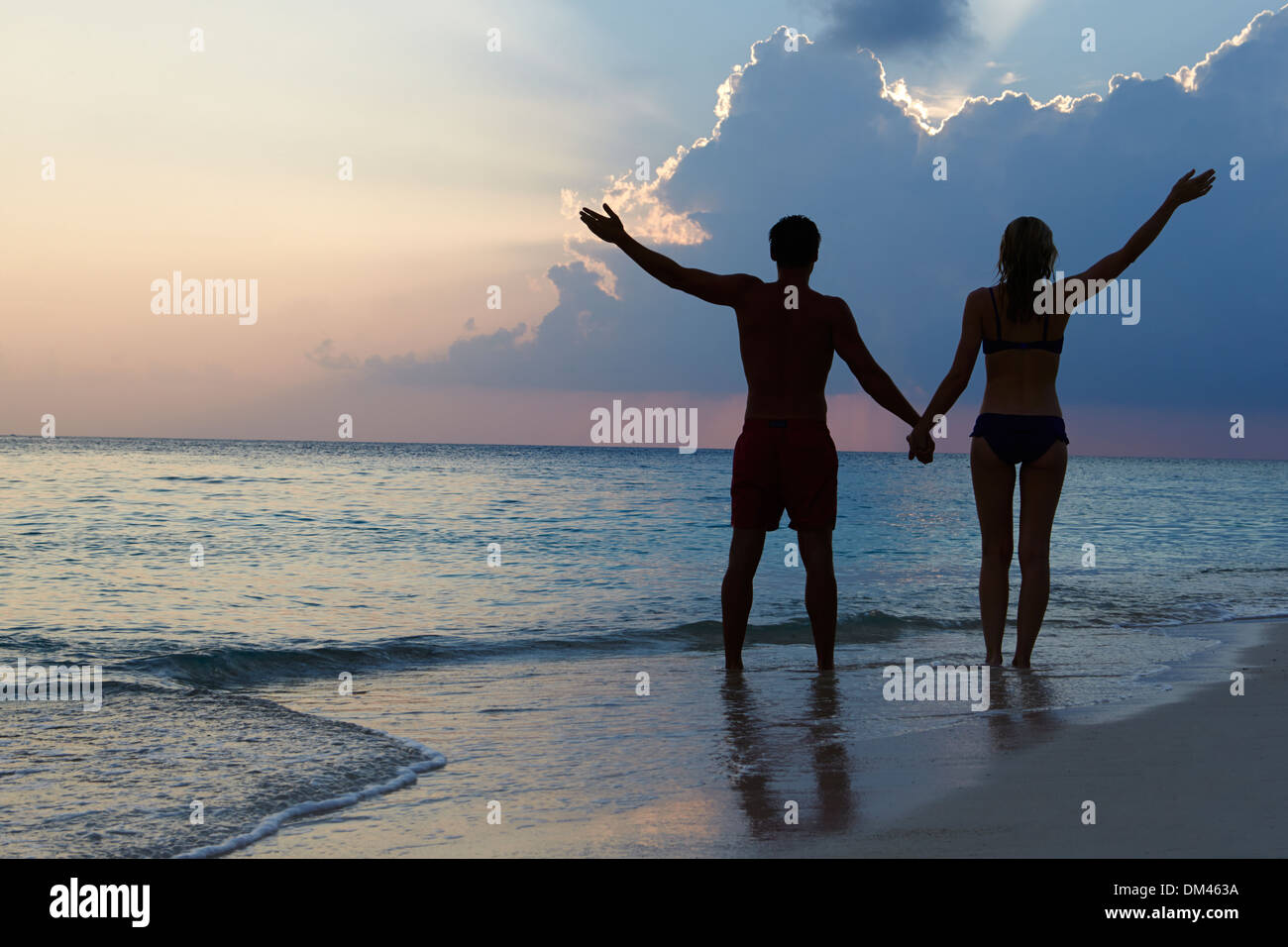 Silhouette eines Paares zu Fuß am Strand bei Sonnenuntergang Stockfoto