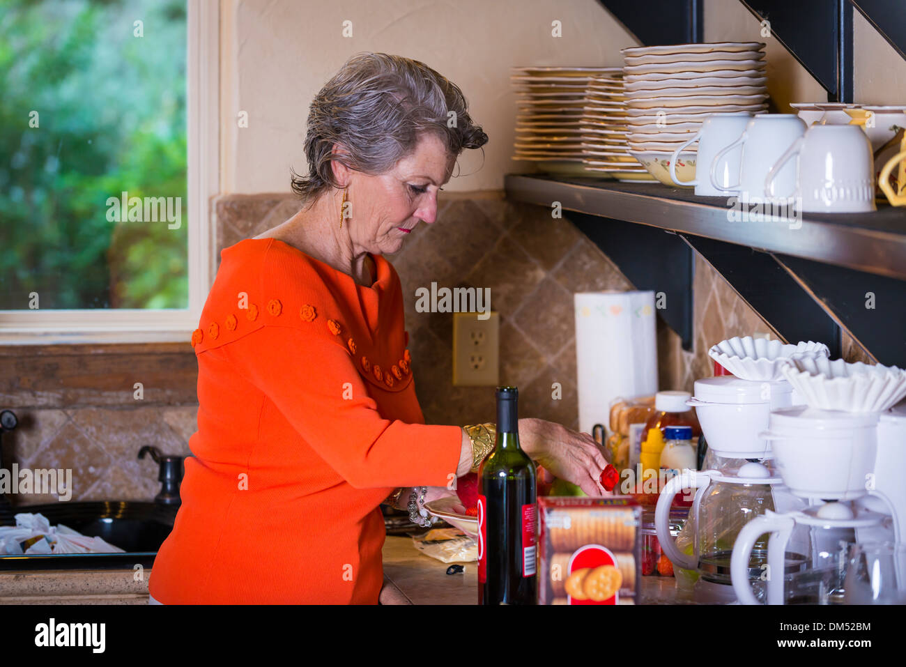 Reife Frau, Kaukasier, 59 Jahre alt, ist Zubereitung von Snacks in ihrer Küche für eine Grillparty. Stockfoto
