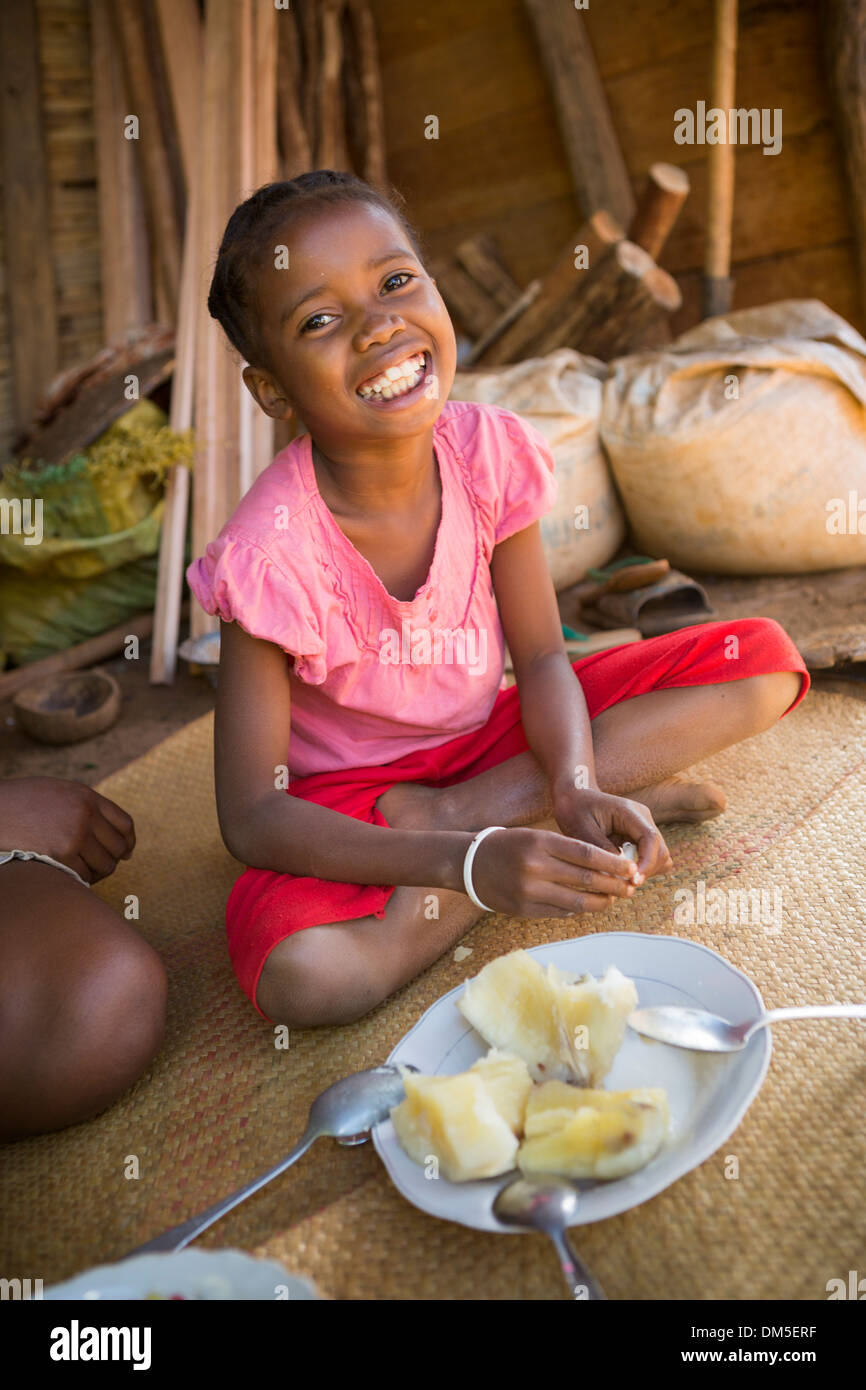 Ein Kind isst Maniok in Fenerive Est Bezirk, Madagaskar Stockfotografie