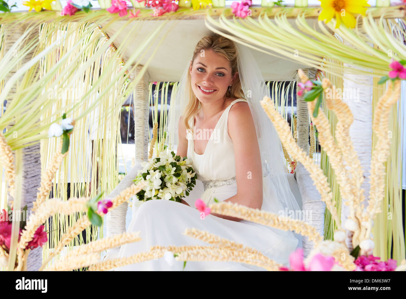 Braut sitzt unter verzierten Baldachin bei Hochzeit Stockfoto
