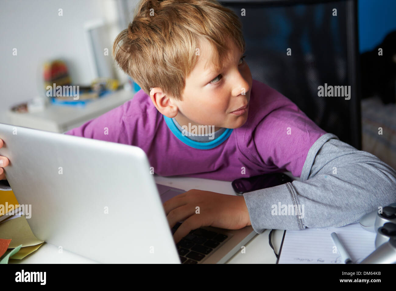 Junge verdächtig verhält, während mit Laptop Stockfoto