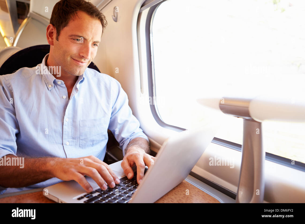 Mann mit Laptop im Zug Stockfoto