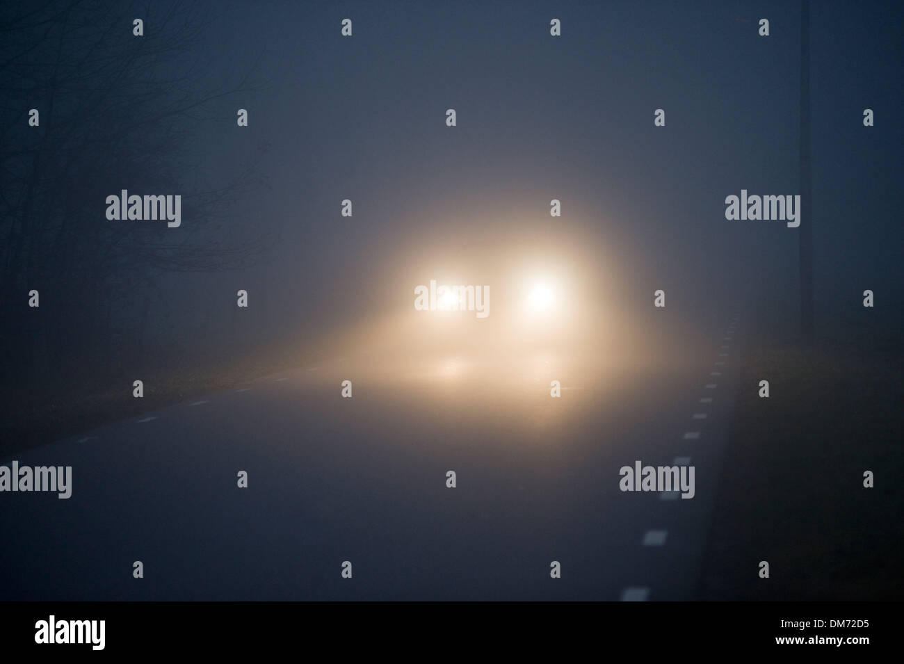 Ein Auto ist langsam im Nebel auf einem Dezemberabend in den Niederlanden fahren Stockfoto