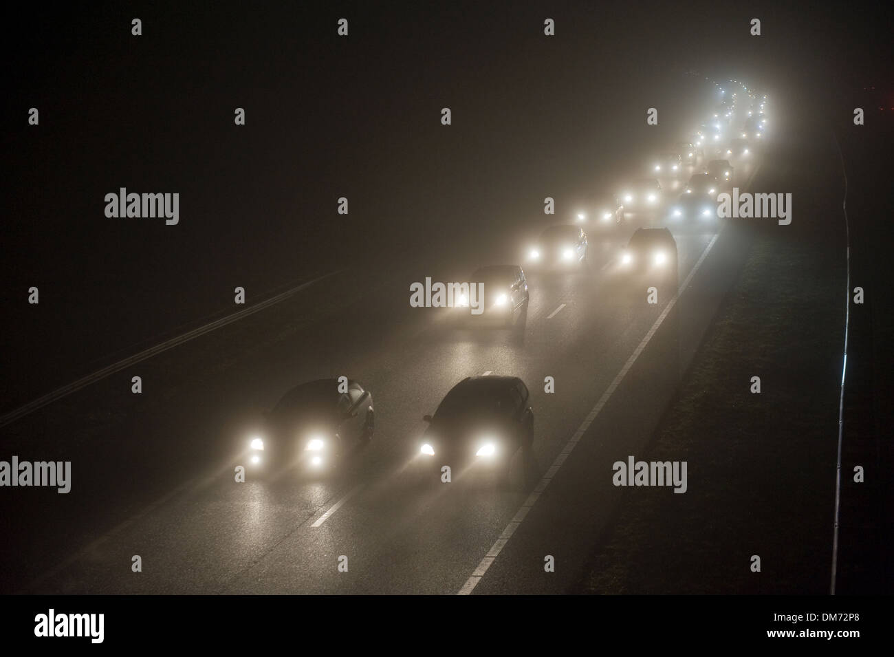 Ein Konvoi an einem nebligen Abend auf einer Autobahn im Dezember in den Niederlanden Stockfoto