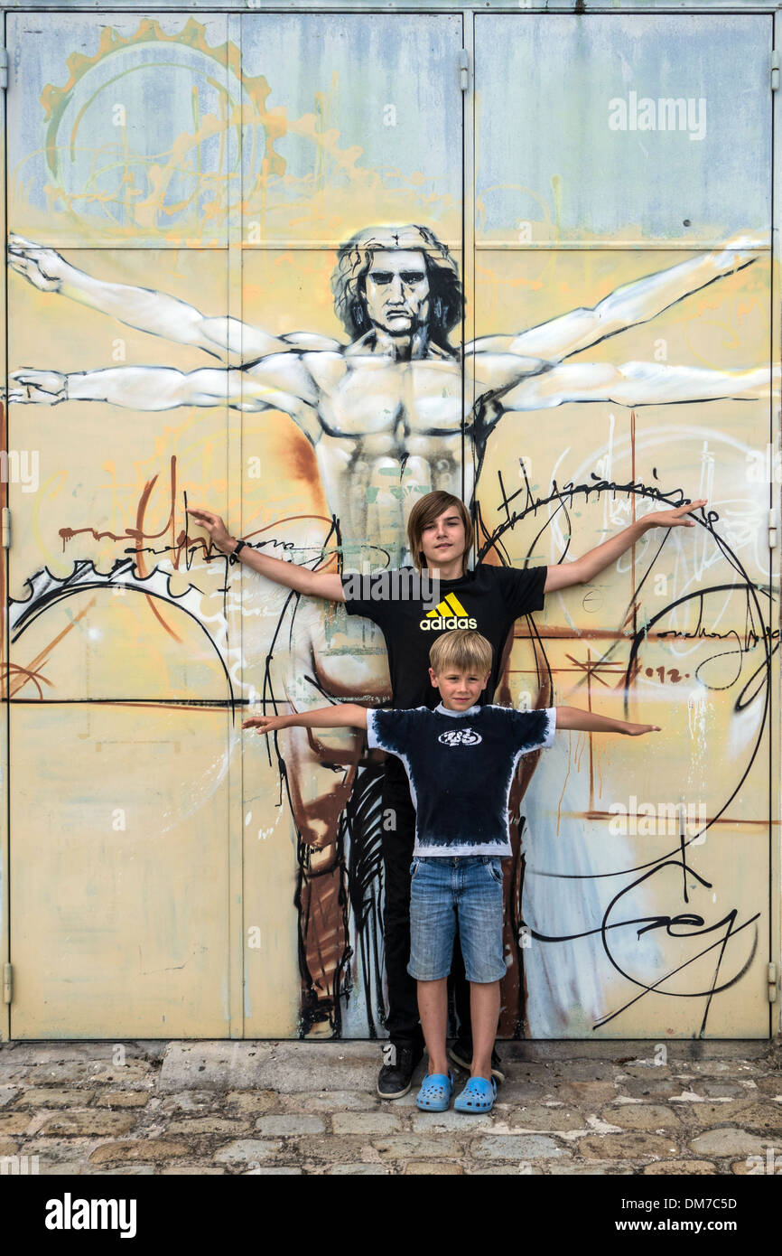 KINDER MIT VERSCHRÄNKTEN ARMEN VOR DER VITRUVIANISCHE MENSCH, ANATOMISCHE ZEICHNUNG VON LEONARDO DA VINCI, ROCHEFORT, CHARENTE-MARITIME (17), FRANKREICH Stockfoto