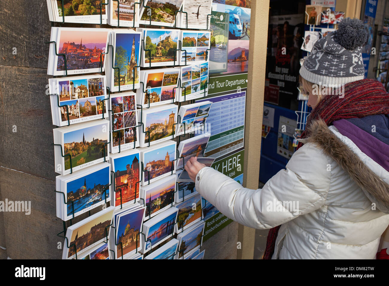 Eine junge Frau schaut Postkarten im Stadtzentrum von Edinburgh Stockfoto