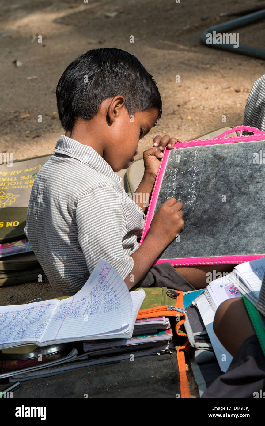 Indische Bauerndorf Schuljunge auf einem Kreide-Tablet in einer externen Klasse schreiben. Andhra Pradesh, Indien Stockfoto