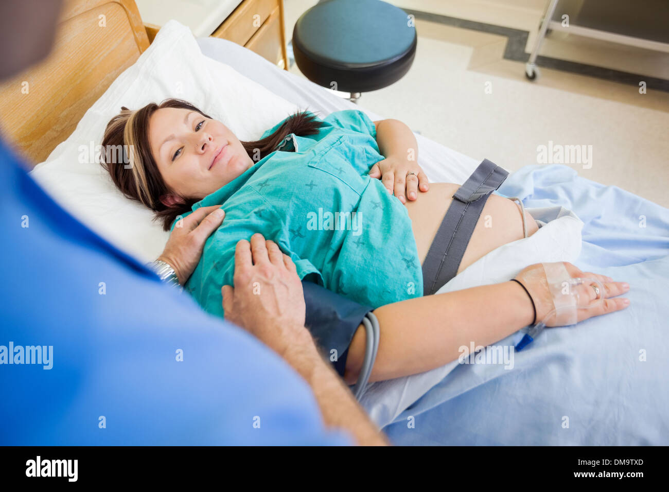 Schwangere Frau lächelnd während wird von Ehemann In Kra getröstet Stockfoto