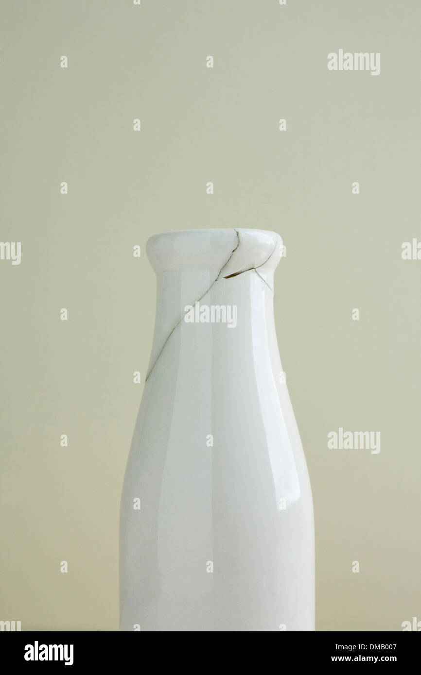 Eine gebrochene Milch Glas oder Vase wurde behoben, Risse, auf eine Creme Hintergrund zeigen. Stockfoto