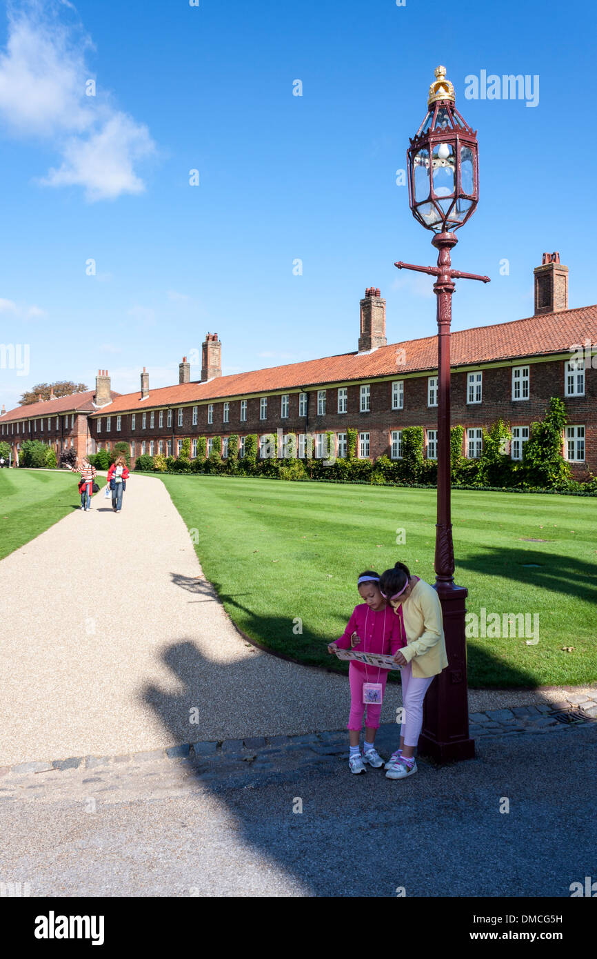 Zwei junge Mädchen schauen Sie sich eine Karte und touristische Führer am Eingang nach Hampton Court Palace, London, England, GB, UK. Stockfoto