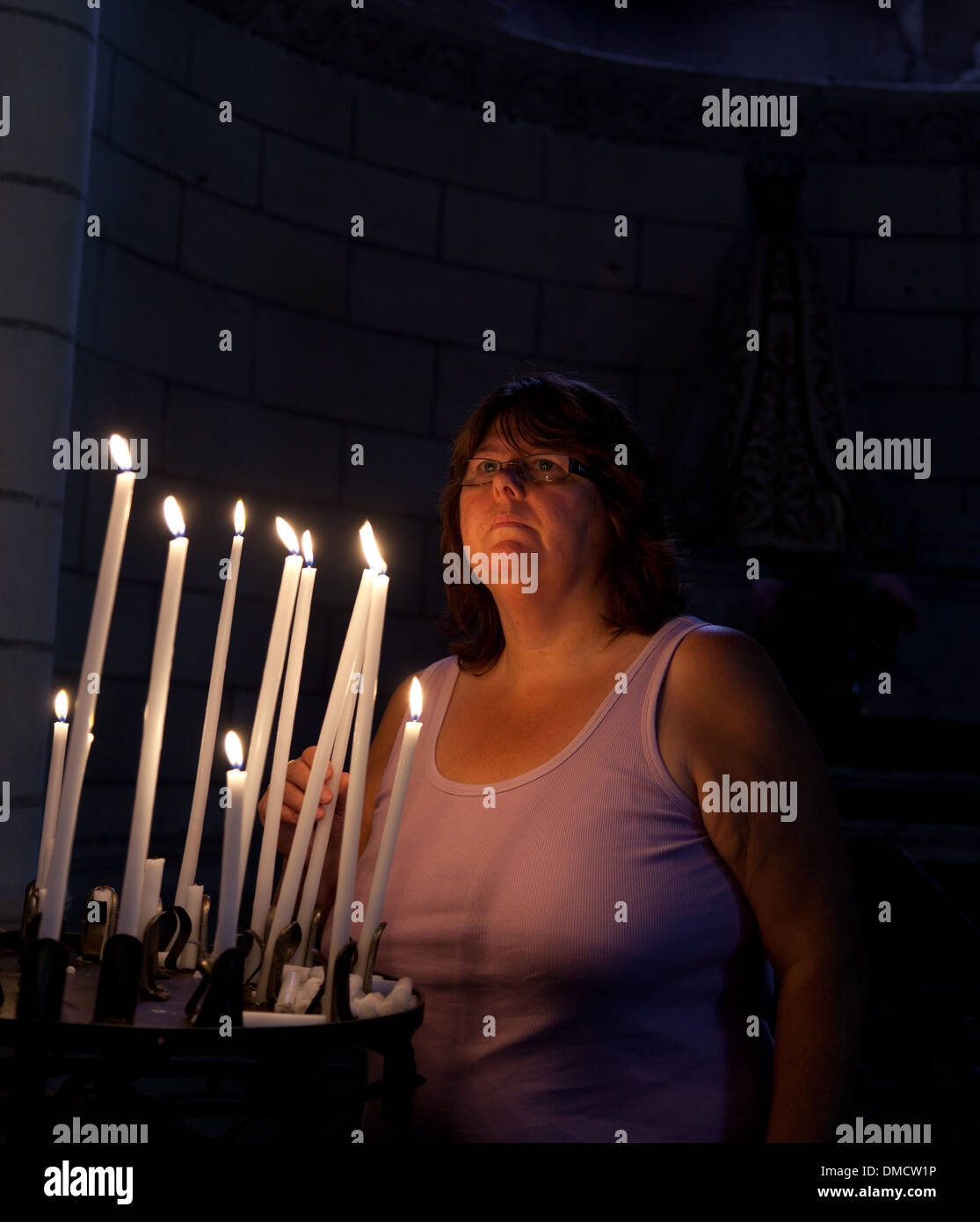 Frau in der französischen Kirche anzünden von Kerzen Stockfoto