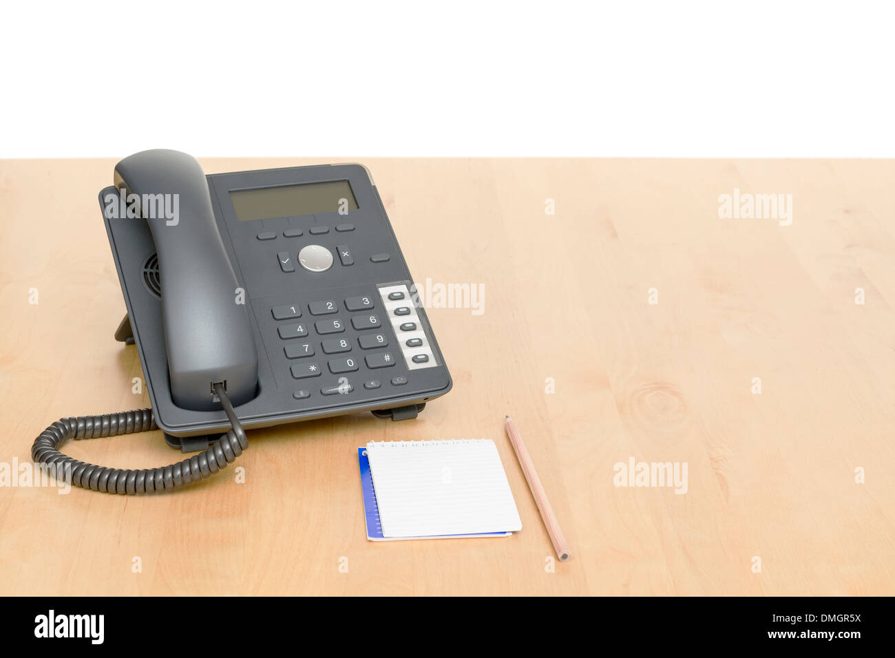 Telefon am Schreibtisch mit Notepad in weißem Hintergrund. Schreibtisch aus Holz. Stockfoto