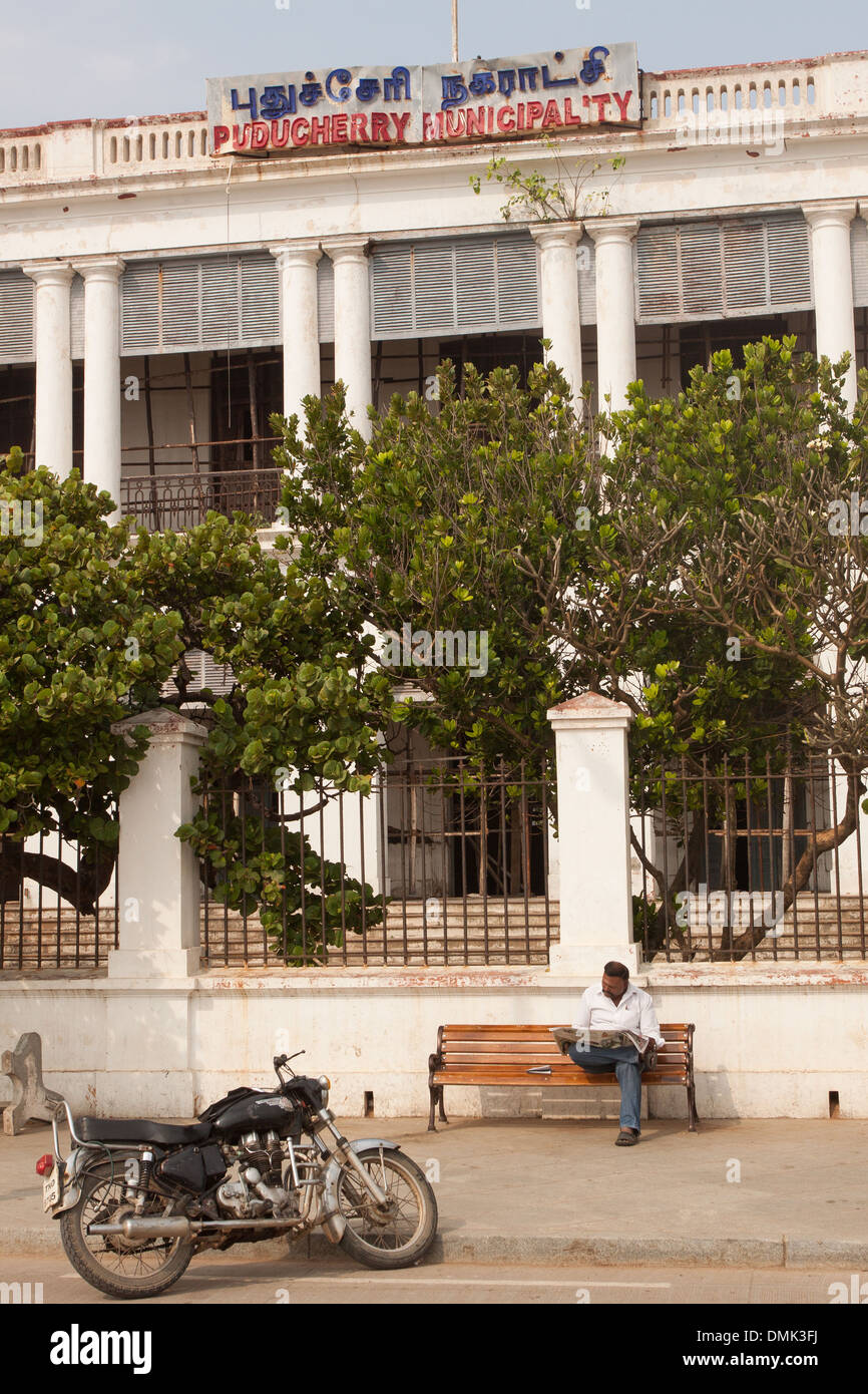 INDISCHE LIEST SEINE ZEITUNG VOR DEM ALTEN RATHAUS VON PONDICHERRY, FRENCH QUARTER, EHEMALIGEN FRANZÖSISCHEN HANDELSPOSTEN VON PONDICHERRY, PUDUCHERRY, HAUPTSTADT DES TERRITORIUMS VON PONDICHERRY, INDIEN Stockfoto