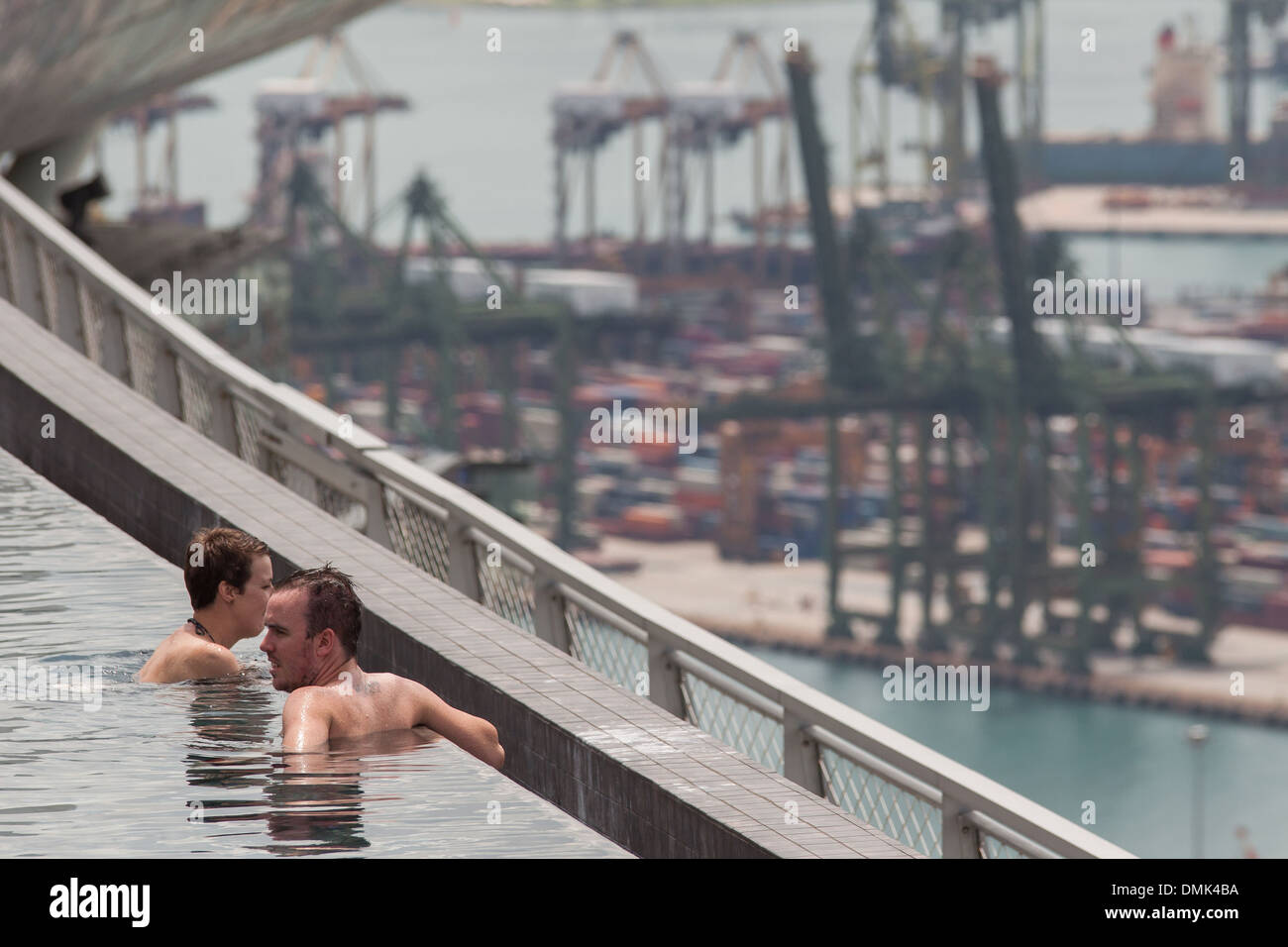 GÄSTE GENIEßEN DEN INFINITY-POOL AUF DEM DACH DES HOTEL MARINA BAY SANDS MIT, IM HINTERGRUND, VERSAND, CONTAINER UND DEN HANDELSHAFEN VON SINGAPUR, MARINA BAY, SINGAPUR Stockfoto