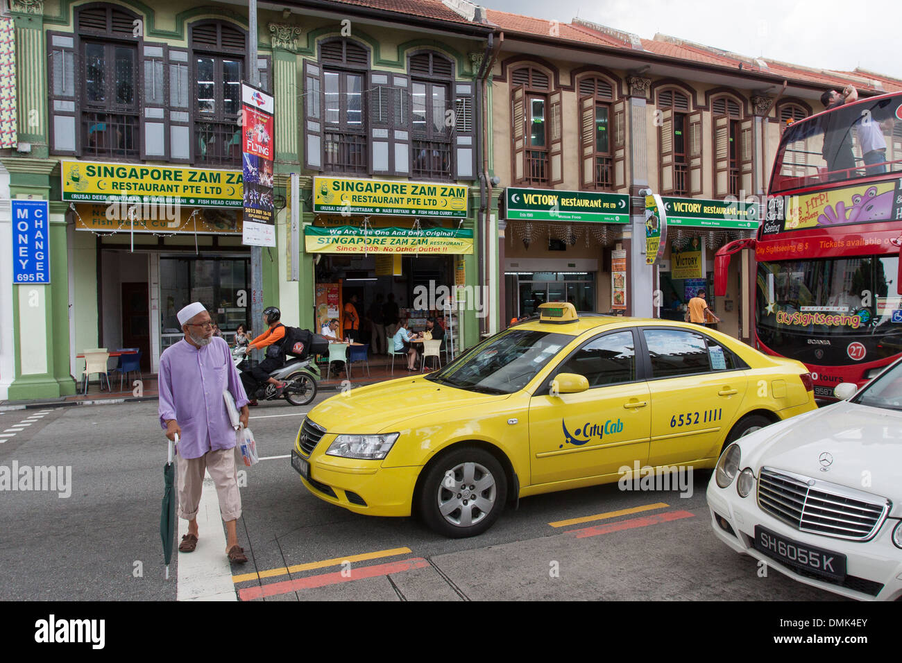 TAMIL INDISCHE VOR EIN TAXI CROSSING NORTH BRIDGE ROAD, NACHBARSCHAFT VON KAMPONG GLAM, SINGAPUR Stockfoto