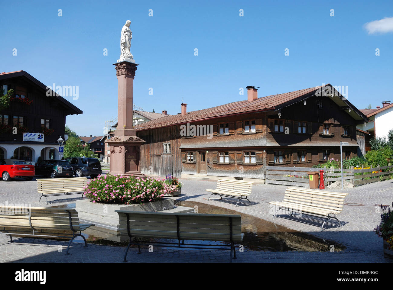 Allgäuer Bauernhaus aus dem 19. Jahrhundert in Oberstaufen mit Marian Column im Vordergrund. Stockfoto