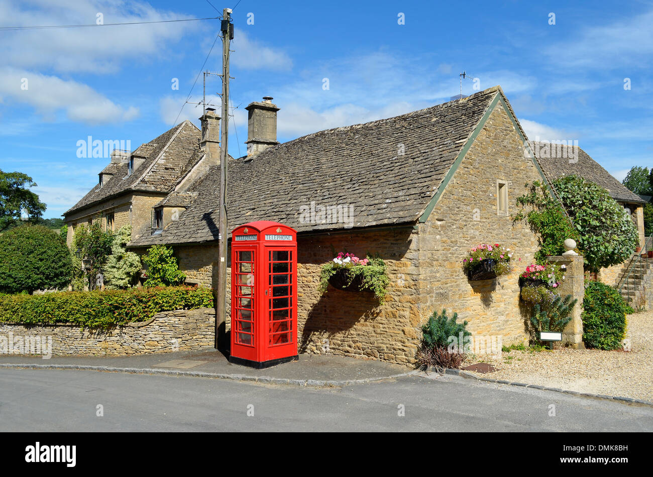 Honig-farbigen Häusern aus Stein und eine rote Telefonzelle in einem Dorf in den Cotswolds im ländlichen England. Stockfoto