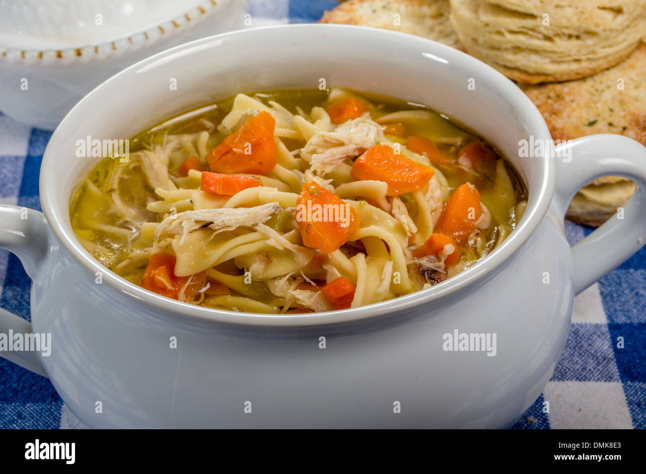 Warme Hühnersuppe und frisch gebackenen Brötchen auf blauem aufgegebenen Stoff Stockfoto