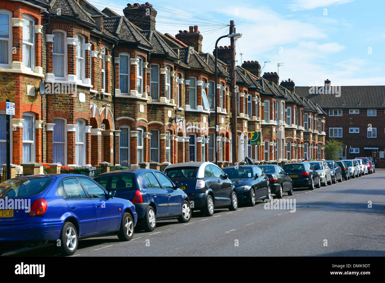 East London Street Scene Linie von geparkten Autos in Straße und Reihe von Reihenhäusern mit Bewohnern Parkplatz West Ham Newham London UK Stockfoto
