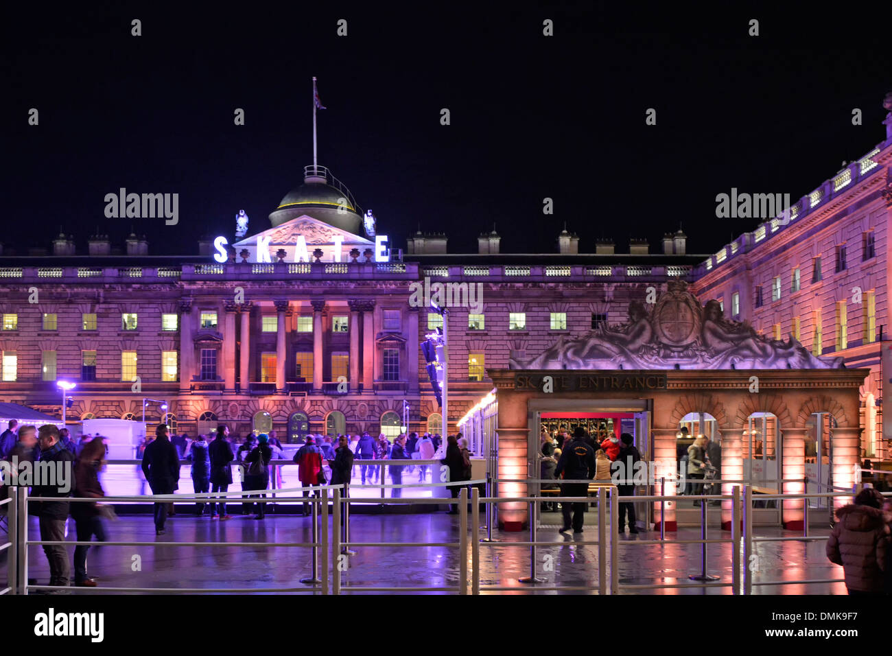 Die Leute beobachten Eisläufer Somerset House Nacht Flutlicht Fassade Historisches Gebäude um temporäre Winter Eislaufbahn im Innenhof London, Großbritannien Stockfoto