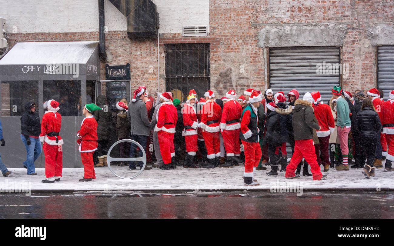 Weihnachtsmänner und ihrer Elfen außerhalb der Grey Lady Bar im Stadtteil Lower East Side von New York während der jährlichen SantaCon auf Samstag, 14. Dezember 2013.  SantaCon, in erster Linie eine Kneipentour in Santa und andere Weihnachten im Zusammenhang mit Kostümen, zieht Tausende von Masken gehen von Bar zu Bar. Der Trinker wurden aufgefordert, in den Einrichtungen zu trinken, Spielzeug für Kleinkinder teilnehmen. In diesem Jahr einige Gemeinden beschweren sich über Erbrechen, öffentliche Urinieren und andere Phänomene, die das Ereignis, was eine Razzia der Polizei und Transit begleitet. (© Richard B. Levine) Stockfoto