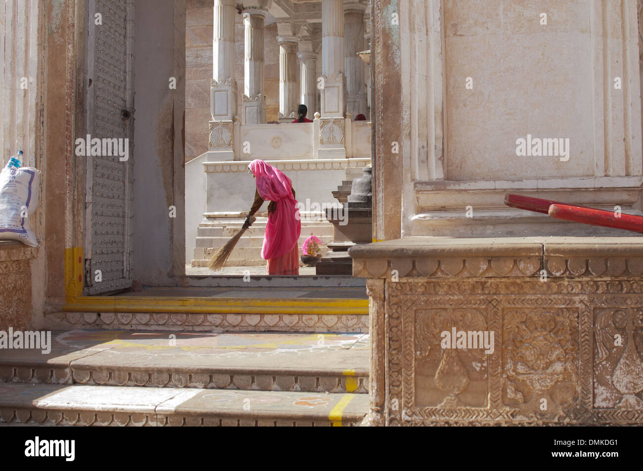 Eine Frau in einem hellen rosa Sari kehren in einem Hindu-Tempel. Stockfoto