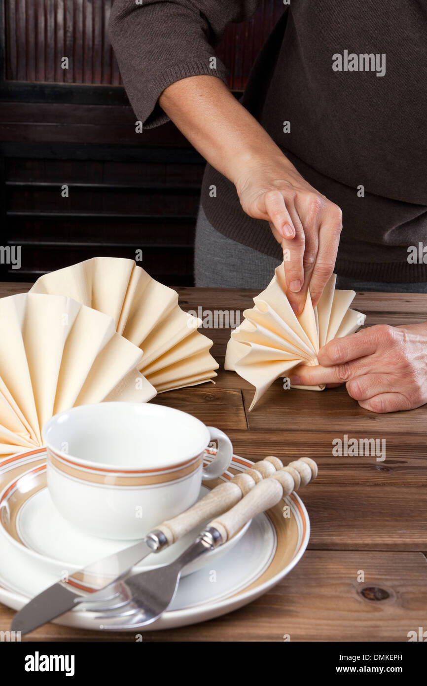 Hände falten schöne Servietten auf einen Mittagstisch Stockfoto