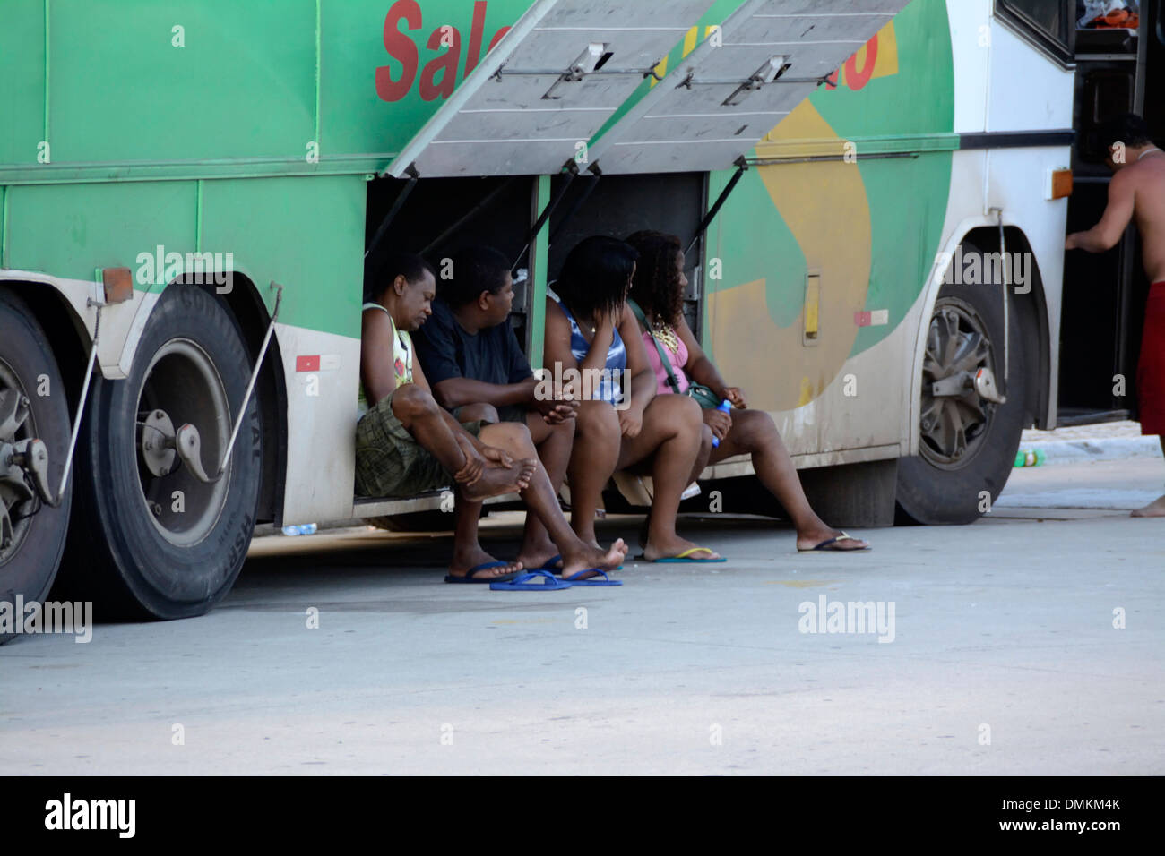 Eine Gruppe brasilianischer Touristen, die im Schatten auf ihren Reisebus am Strand von der Küste von Rio de Janeiro, Brasilien, warten Stockfoto