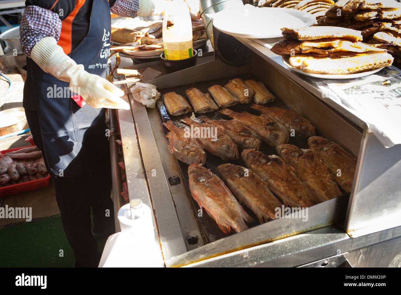 Frau braten frische ganze Fische auf Grillplatte am Jagalchi Shijang (traditionelle outdoor-Markt) - Busan, Südkorea Stockfoto