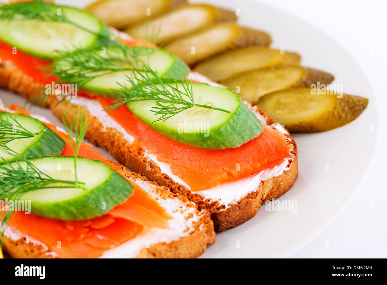Lachs Sandwiches mit frische und eingelegte Gurken auf Platte Closeup Bild. Stockfoto