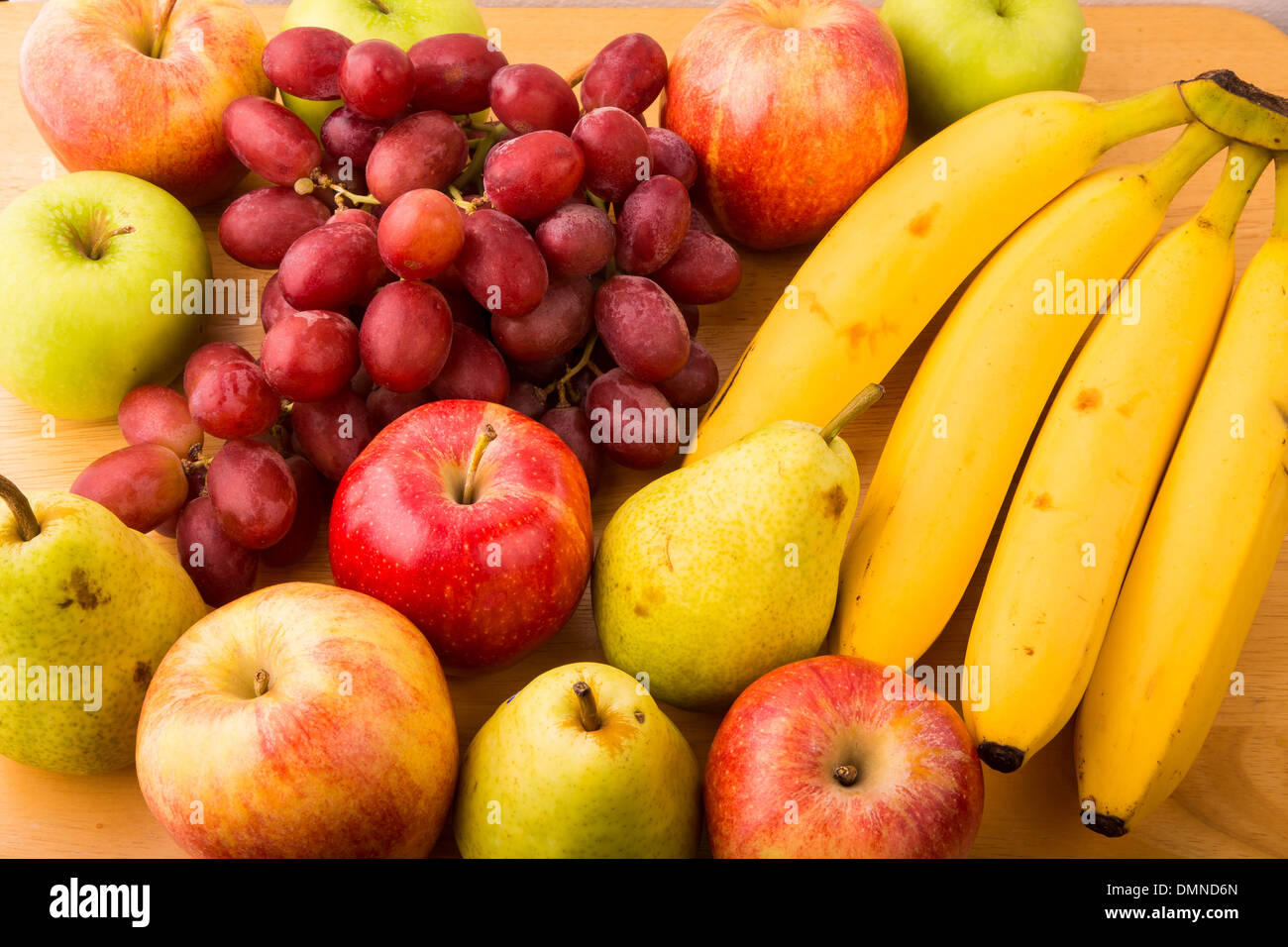 Nahaufnahme von frischen Bananen, Birnen, Äpfel und Trauben auf einem Holztisch Stockfoto