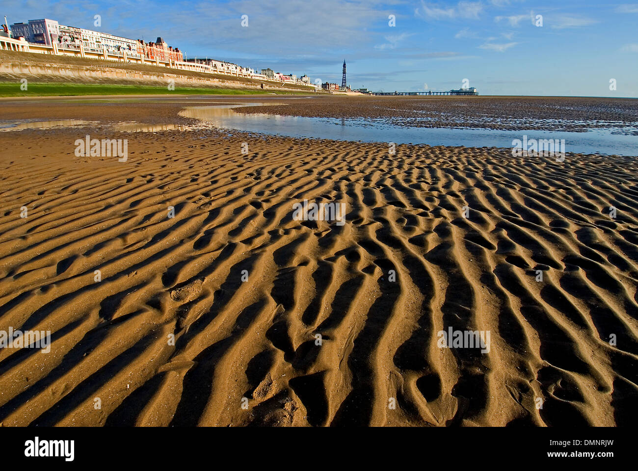 Ebbe in der irischen See macht weite Gebiete des plätschernden Sandstrände Blackpools Strandpromenade entlang. Stockfoto