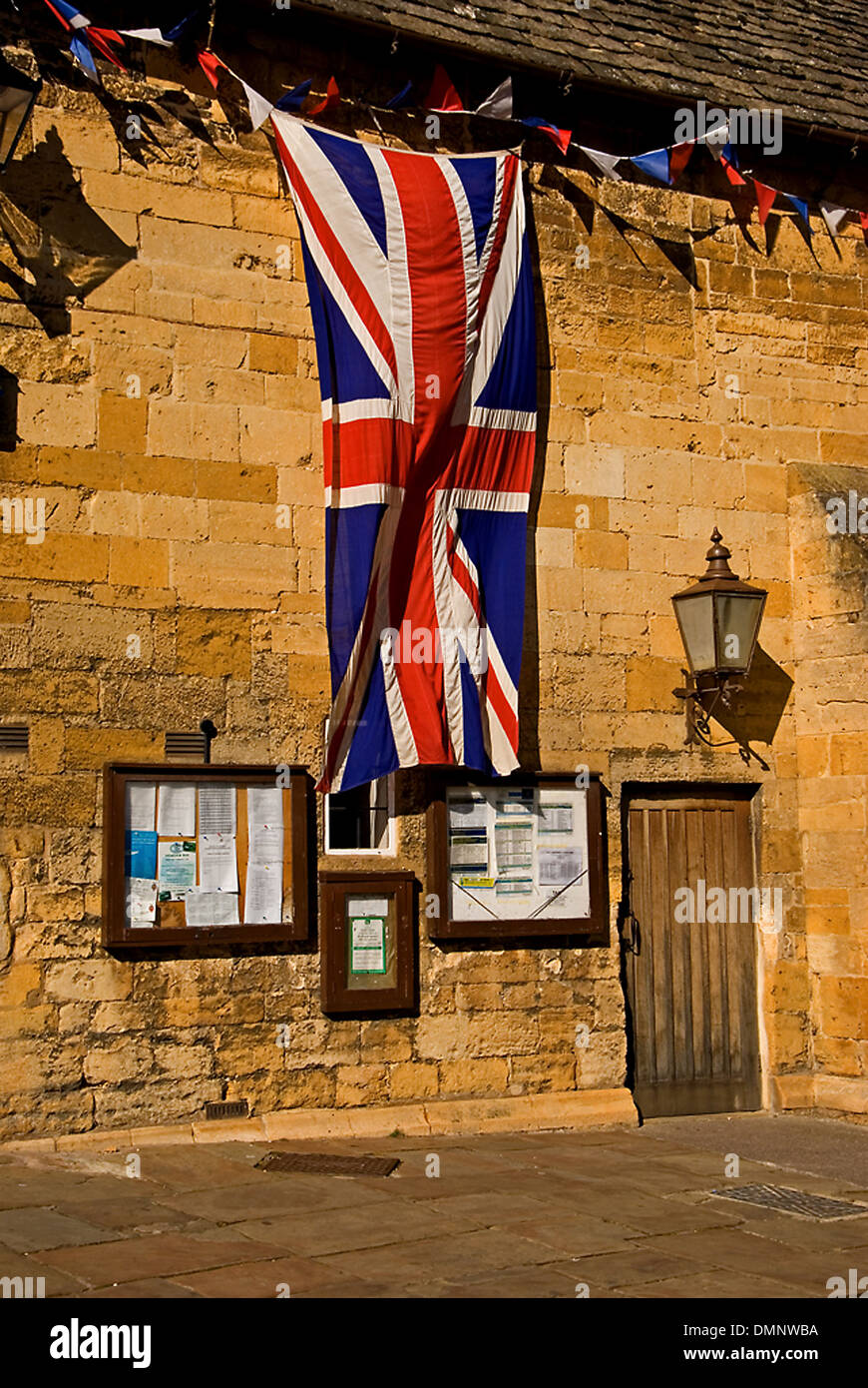 Gebäude aus Stein mit großen Union Jack, die Flagge von Großbritannien hängen von der Traufe des Markthalle im Cotswold Marktstadt Chipping Campden. Stockfoto