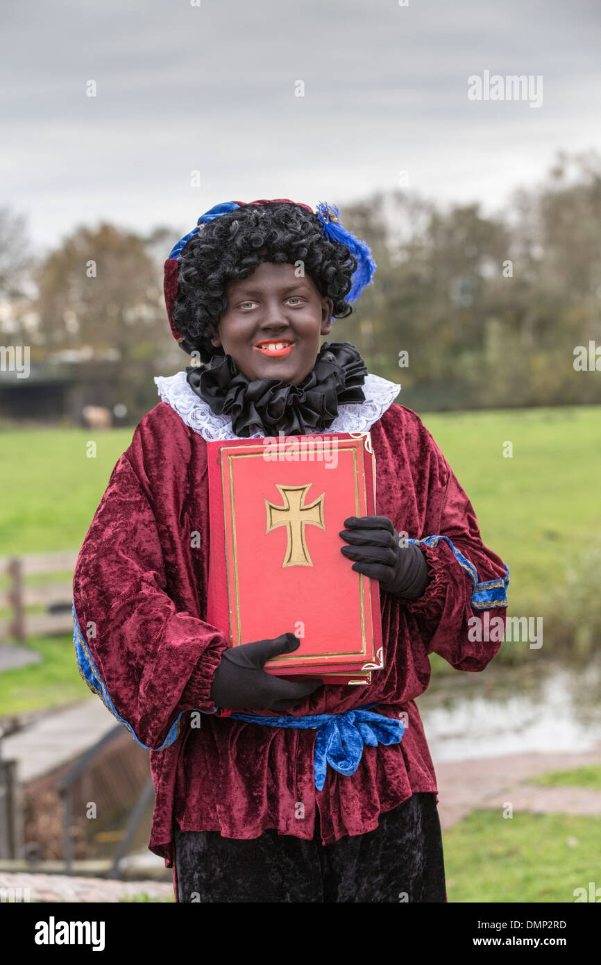 Niederlande,'s-Graveland, Saint Nicholas Vorabend am 5. Dezember. Black Pete trägt heiliges Buch Stockfoto